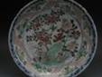 This is Chinese Famille Candy Dish , painted in green, red and grey, outlined in black, with peonies, rockwork and grasses, banded border, with shaped panels with lemons and foliage, cobalt blue border with stylised leaves and scrolls, 34cm diam, flower