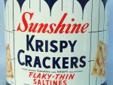 Sunshine Krispy Crackers Tin 15 oz. Trade Marks Sunshine and Krispy Registered Flaky-Thin Saltines, Crispy Flaky and Flavorful, Containing Flour, Shortening, Powdered Whey, Salt, Soda, Yeast. From the Thousand Window Bakeries. It measures 6 1/4" diameter